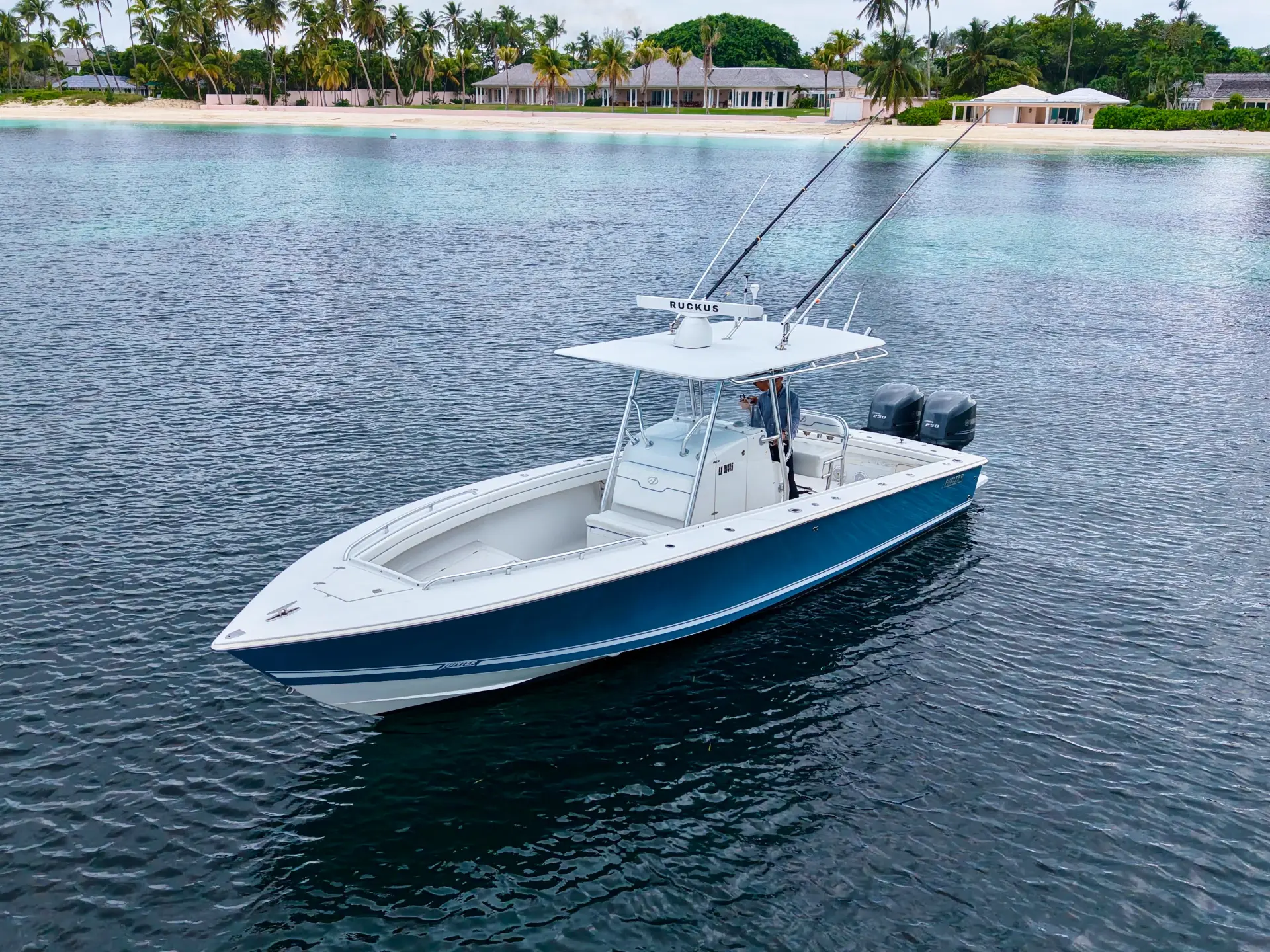 Ethan Maura’s private boat at anchor in a Bahamian bay, with waterfront homes along the shoreline behind